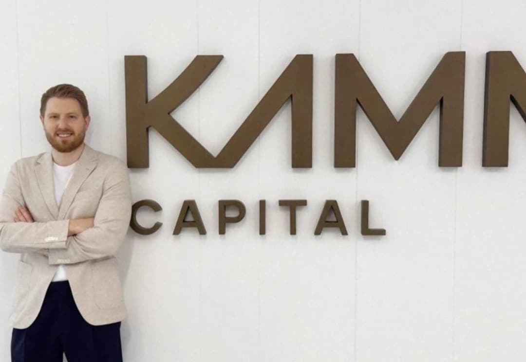 Dane Baker standing next to Kama Capital sign